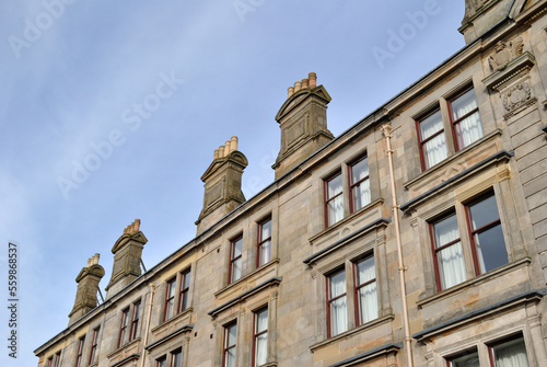 Facade of Old Stone Tenement Building with Classical Chimneys and Blue Sky