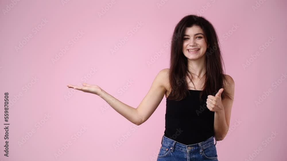 4k slow motion video of one girl pointing at left over pink background. 4k slow motion video of one girl pointing at left over pink background.