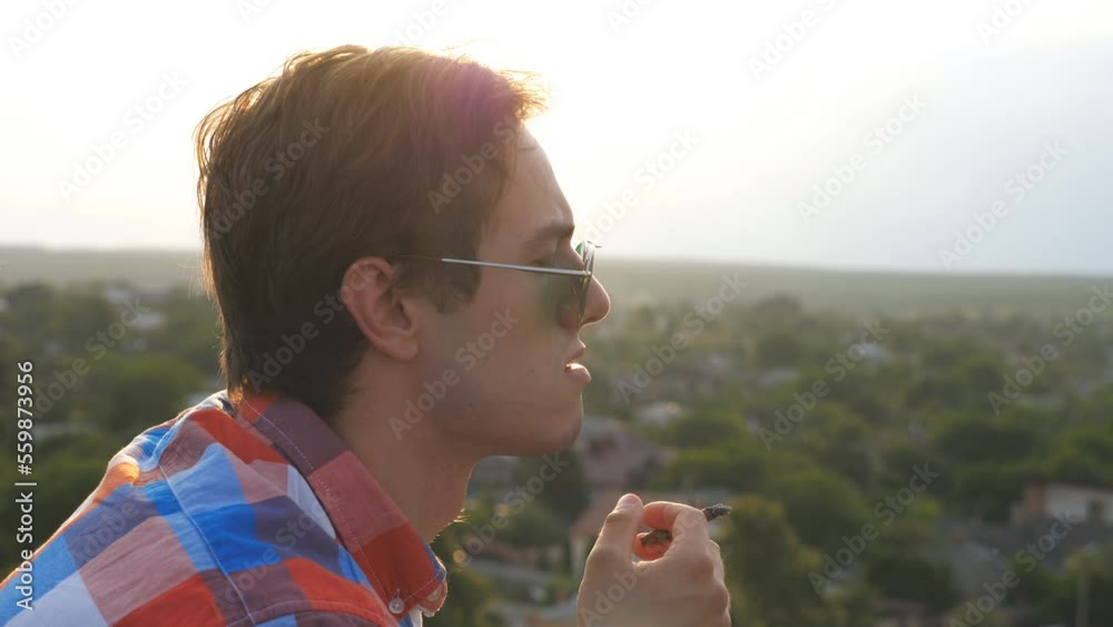 Profile of handsome man in sunglasses standing on the edge of rooftop ...