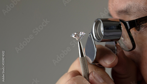 Schilderij op canvas Diamond dealer evaluates the quality of round cut diamond through magnifying glass