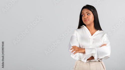Serious thoughtful millennial black lady in white blouse thinking, creating idea for startup
