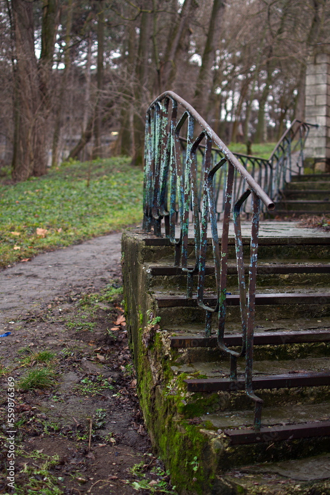 Old abandoned concrete staircase covered with moss with metal railings