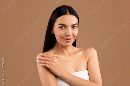 Sexy young woman posing topless on beige studio background