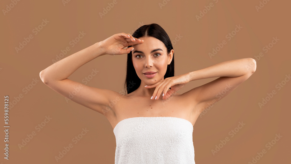 Portrait of beautiful young woman touching her face on beige Portrait of beautiful young woman touching her face on beige