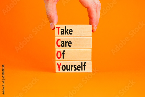 TCOY take care of yourself symbol. Concept words TCOY take care of yourself on wooden block on beautiful orange table orange background. Business TCOY take care of yourself concept. Copy space.