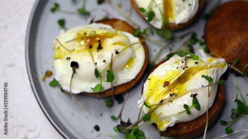 Poached eggs with microgreens on a crispy bun on a plate.