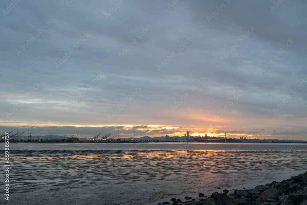 Obraz premium Sunset over San Francisco bay with skyline and port