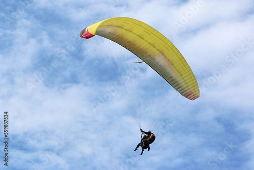 Yellow tandem Paraglider flying in a blue sky