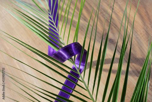 Cross with purple sash and palm leaf on wooden background. Ash Wednesday, Lent season, Holy Week, Good Friday and Palm Sunday concept. photo