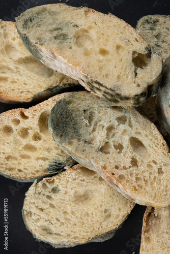 Mold on bread on a black background close-up. The danger of mold  stale products.
