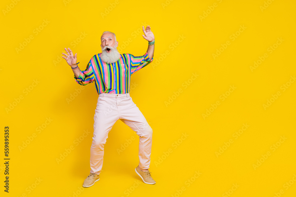 Full length photo of charming impressed man wear colorful shirt enjoying discotheque empty space isolated yellow color background Full length photo of charming impressed man wear colorful shirt enjoying discotheque empty space isolated yellow color background