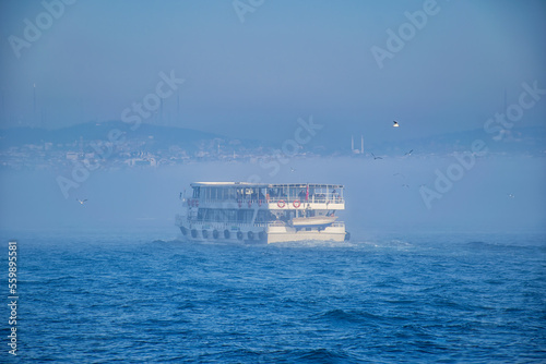 A passenger boat floating in the fog. A boat in Istanbul on a foggy day.
