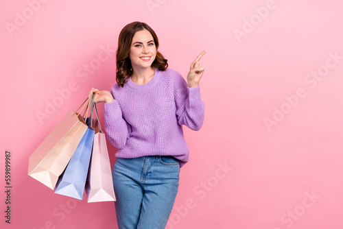 Photo of adorable charming girl dressed purple pullover rising bargains pointing empty space isolated pink color background