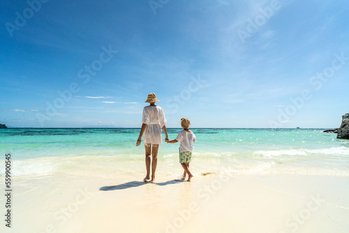 Fototapete Summer photo of mother with son walking on the sandy tropical beach, relaxing, enjoying sunny day on vacation