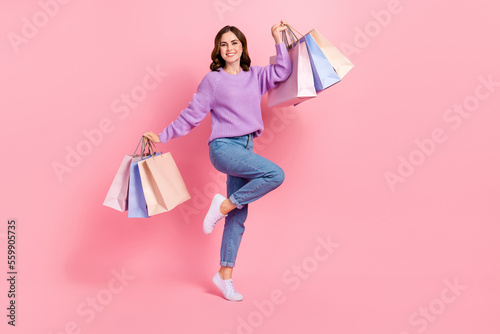 Full length photo of excited lovely girl dressed purple pullover holding shoppers isolated pink color background