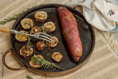 Baked sweet potato on a stone tray with rosemary. Traditional brazilian recipe photo