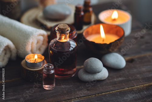 Concept of natural essential organic oils  Bali spa  beauty treatment  relax time. Atmosphere of relaxation  pleasure. Candles  towels  dark wooden background. Alternative oriental medicine