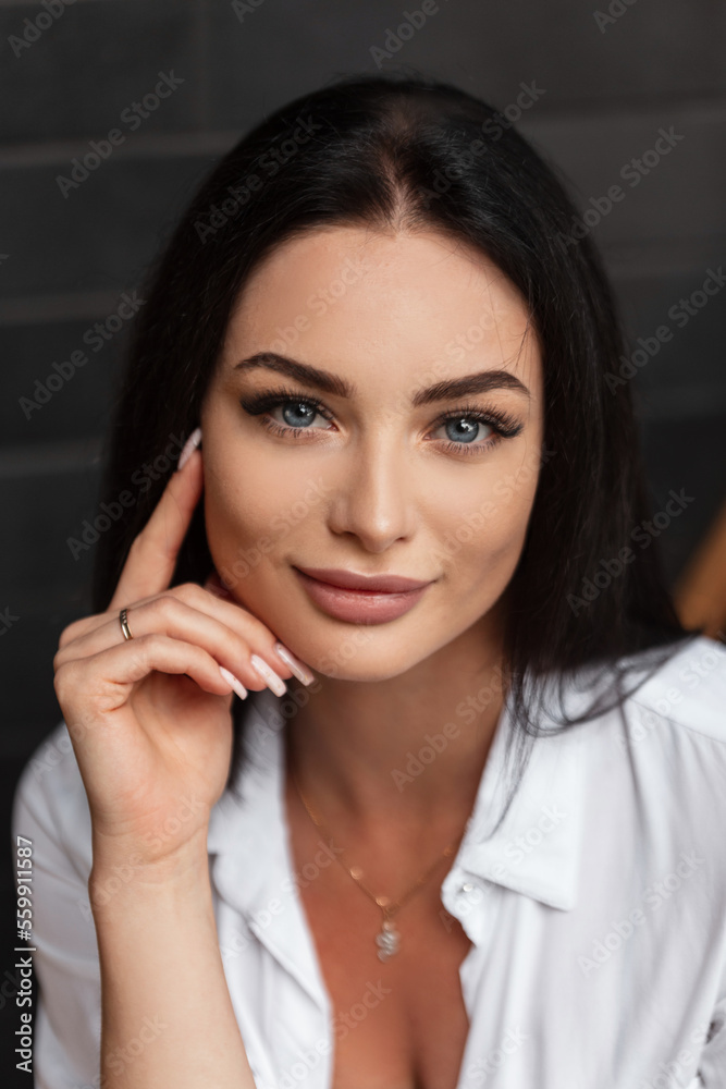 Fashionable beautiful woman with blue eyes and a clean face in a fashion white shirt on a dark background in the city Fashionable beautiful woman with blue eyes and a clean face in a fashion white shirt on a dark background in the city