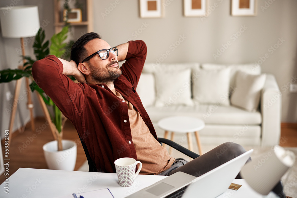Satisfied young man is sitting in a chair in the office after a successful job Satisfied young man is sitting in a chair in the office after a successful job