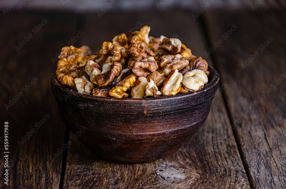 Peeled walnuts in an earthenware dish on a kitchen wooden table