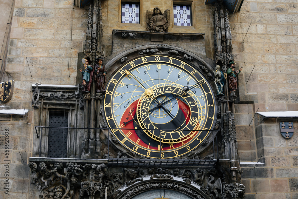 Obraz premium Prague, Czech Republic, 15 December 2022: Old town square with snow at sunny winter day, town hall tower with Astronomical clock Orloj, narrow street, Christmas time, ancient figures flanking clock