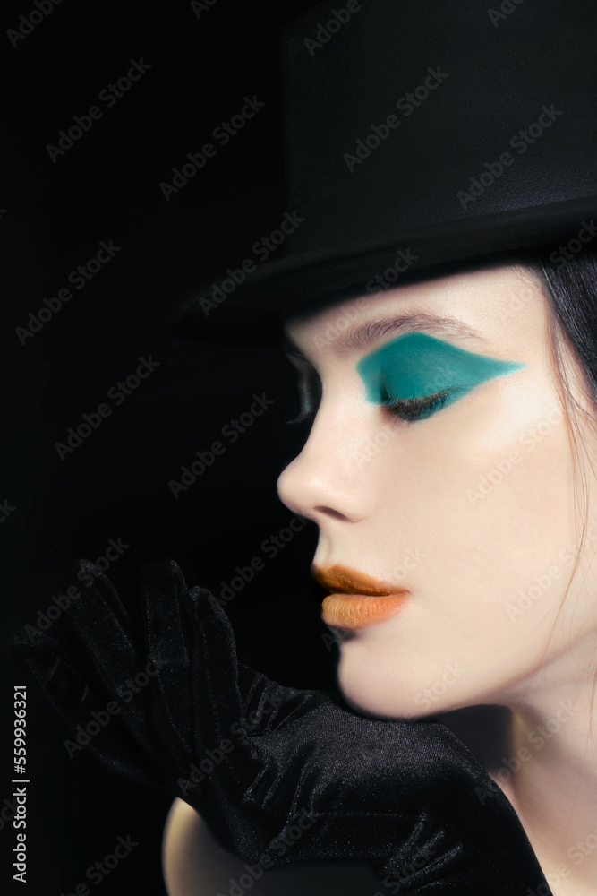 Art-deco makeup at young model with orange lips, green eyeshadows