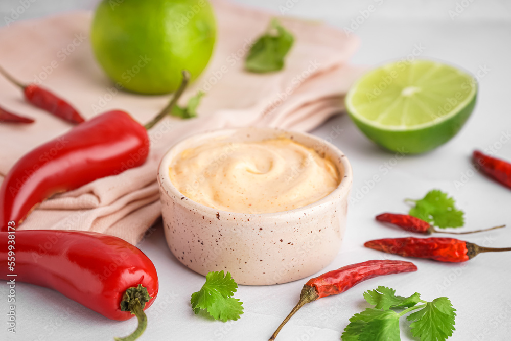 Bowl of tasty chipotle sauce and jalapeno peppers on light background Bowl of tasty chipotle sauce and jalapeno peppers on light background