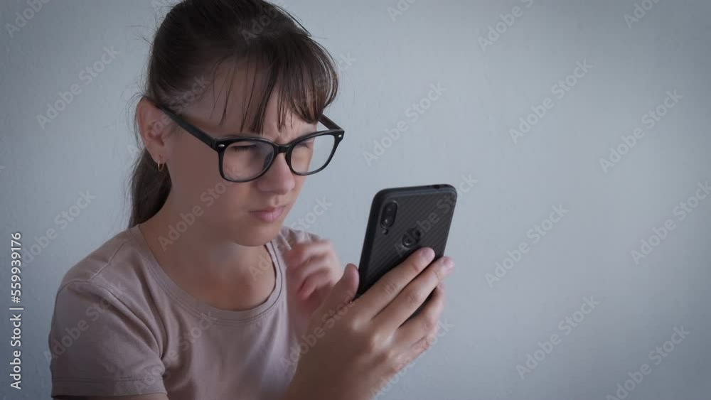 Hold eyeglasses to see phone. A teen girl have interest in her phone and use eyeglasses for better vision in the room. Hold eyeglasses to see phone. A teen girl have interest in her phone and use eyeglasses for better vision in the room.