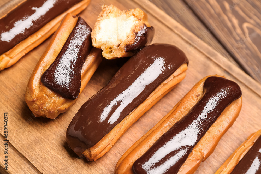 Wooden board with tasty chocolate eclairs, closeup Wooden board with tasty chocolate eclairs, closeup