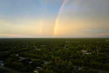 Colorful round rainbow over rural town suburbs against blue evening sky after heavy thunderstorm