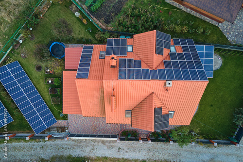 Residential house with rooftop covered with solar photovoltaic panels for producing of clean ecological electrical energy in suburban rural area. Concept of autonomous home
