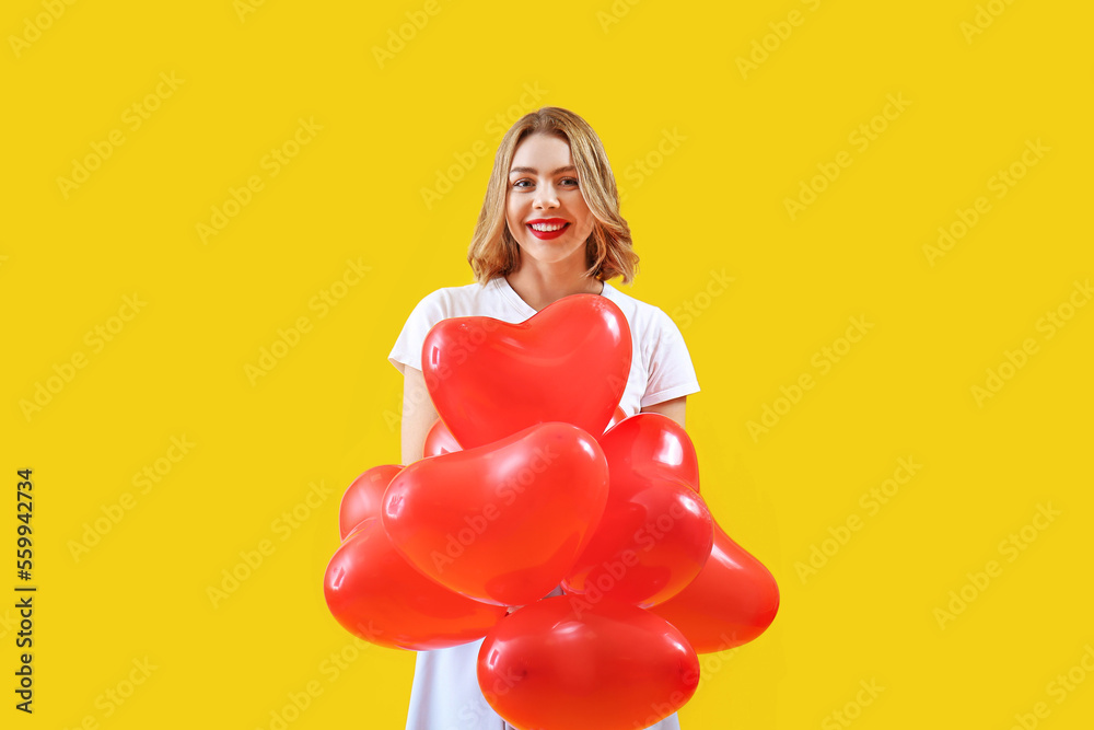 Beautiful young woman with red heart-shaped balloons on yellow background Beautiful young woman with red heart-shaped balloons on yellow background