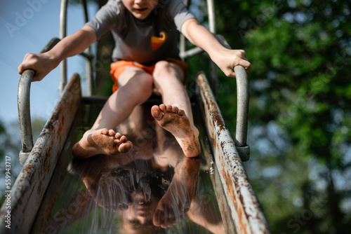 Child's dirty feet sliding down slide on playground at park