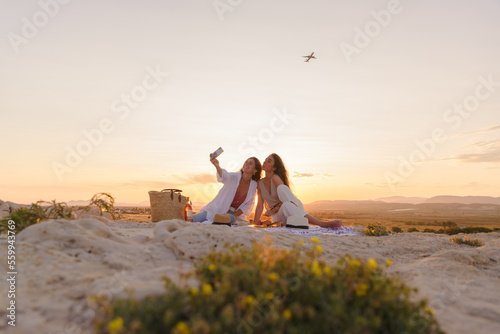 Couple of young women on vacation watch the sunset