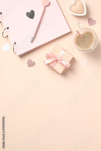 Beige elegant desk table with photo album, gift box, heart shaped candles, coffee cup, decorations. Valentines Day concept.