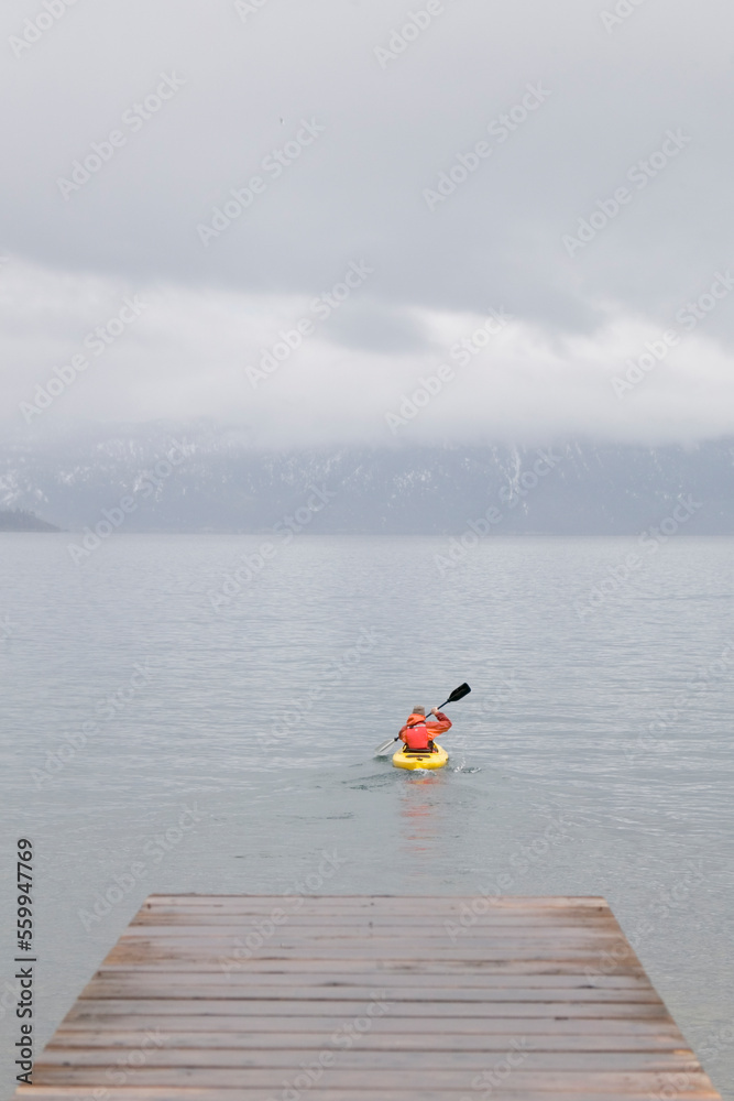 A man kayaking on Lake Tahoe in the fog in winter. A man kayaking on Lake Tahoe in the fog in winter.
