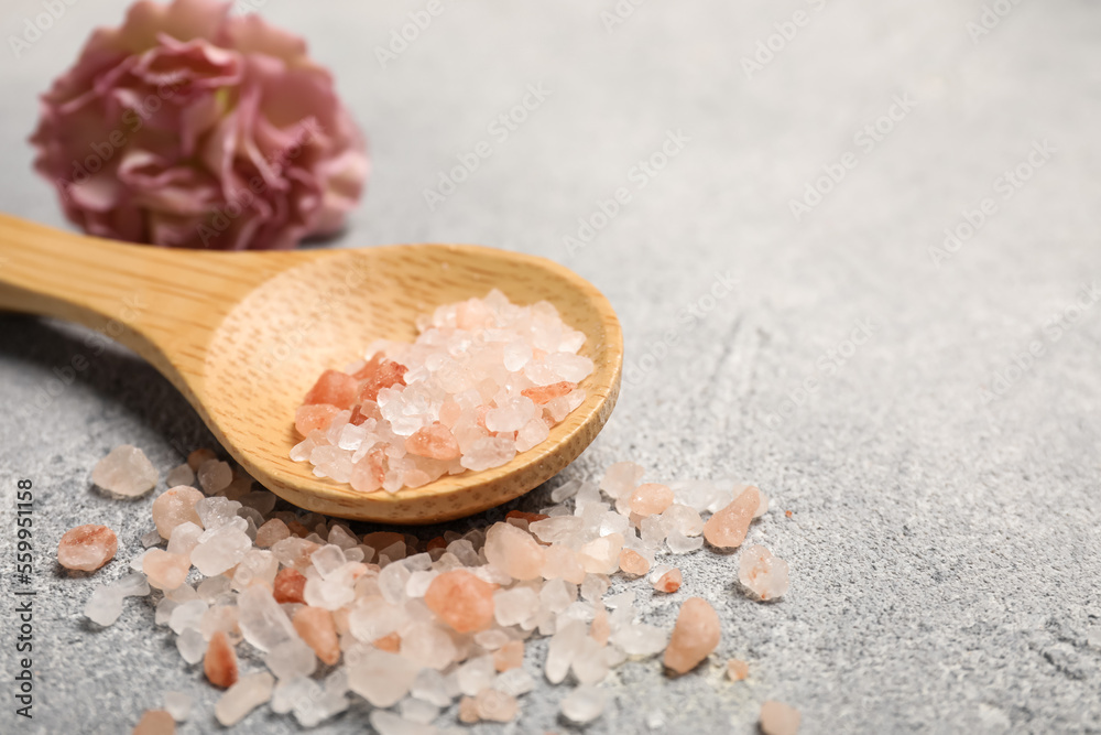 Wooden spoon with natural sea salt and beautiful flower on light grey table, closeup. Space for text Wooden spoon with natural sea salt and beautiful flower on light grey table, closeup. Space for text