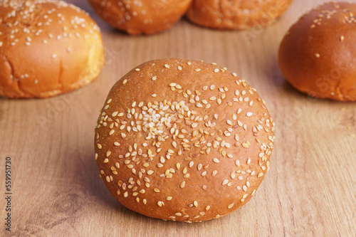 Fresh buns with sesame seeds on wooden table