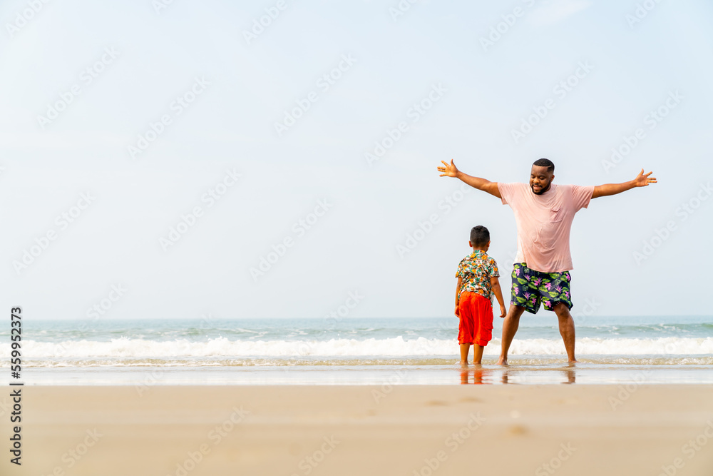 Happy African family on summer holiday vacation. Father playing with little son at tropical island beach at sunset. Parent and boy kid enjoy and fun outdoor lifestyle activity together at the sea.