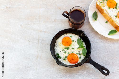 Healthy breakfast food fried egg in skillet pan and coffee on white wood table.