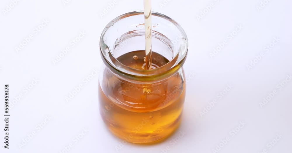 High angle view of pouring honey into honey jar. High angle view of pouring honey into honey jar.