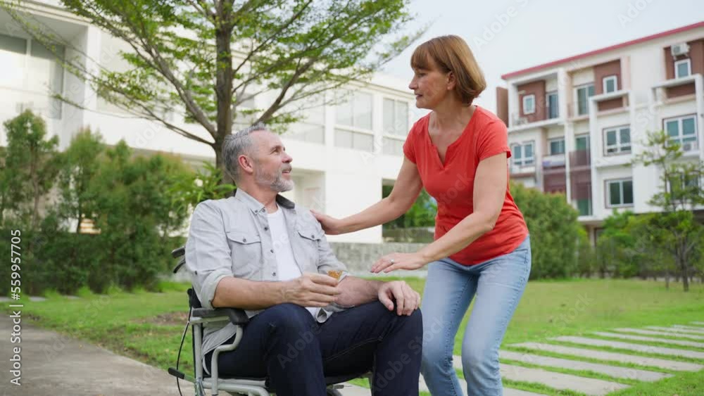 Caucasian senior woman support husband on wheelchair outdoor in garden Caucasian senior woman support husband on wheelchair outdoor in garden