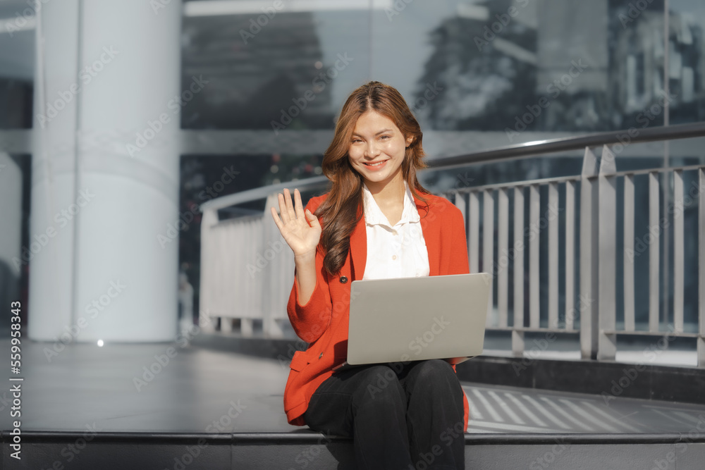Using laptop, Smiling young Asia business woman leader entrepreneur in red color suit working outdoor urban street walk. Using laptop, Smiling young Asia business woman leader entrepreneur in red color suit working outdoor urban street walk.