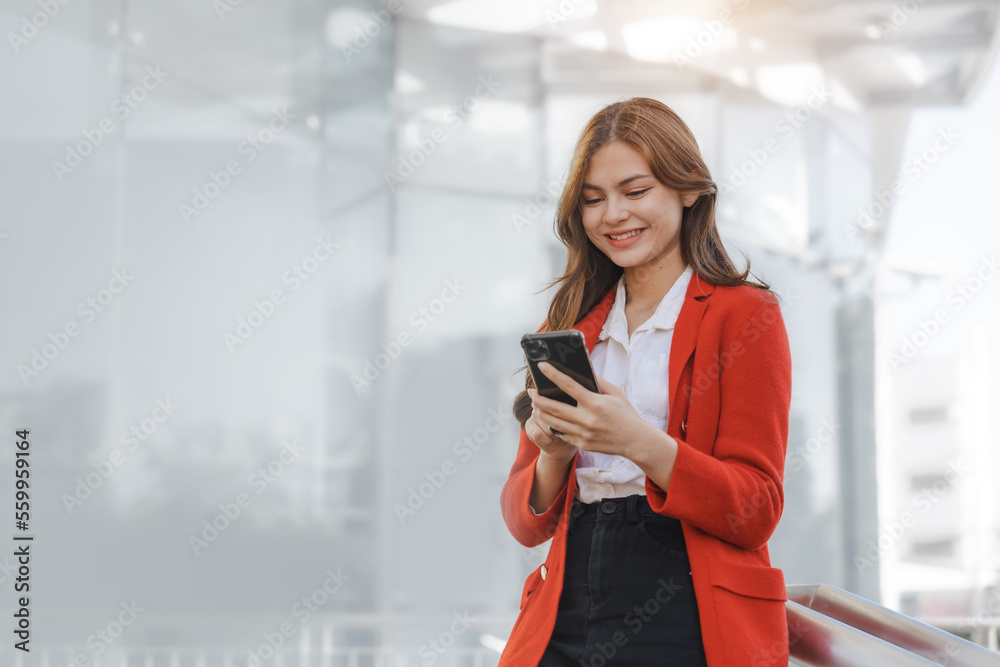 Using mobile, call phone, Smiling young Asia business woman leader entrepreneur in red color suit working outdoor urban street walk. Using mobile, call phone, Smiling young Asia business woman leader entrepreneur in red color suit working outdoor urban street walk.