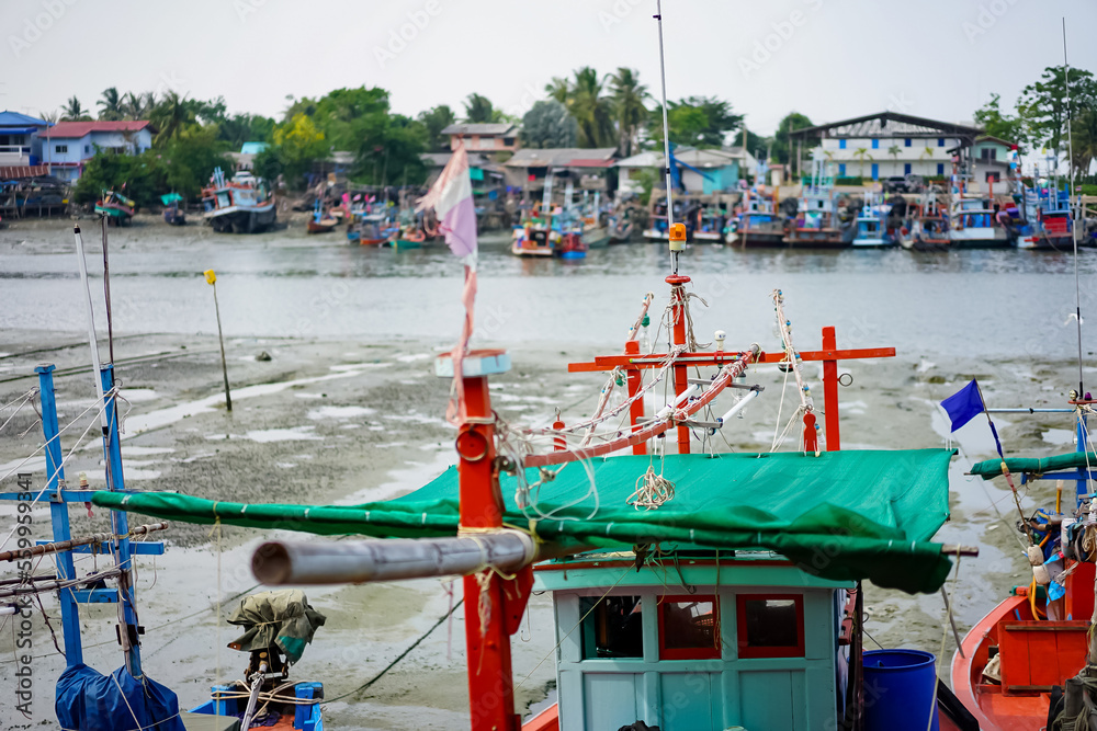 Fishing boats of traditional design add pops of color to the picturesque harbor of Thailand, as they rest at the pier amidst a foreboding sky in the fisherman's valley at year 2017. Fishing boats of traditional design add pops of color to the picturesque harbor of Thailand, as they rest at the pier amidst a foreboding sky in the fisherman's valley at year 2017.