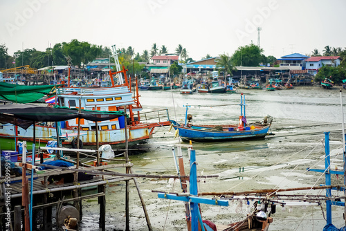 Fishing boats of traditional design add pops of color to the picturesque harbor of Thailand, as they rest at the pier amidst a foreboding sky in the fisherman's valley at year 2017. © Surachetsh