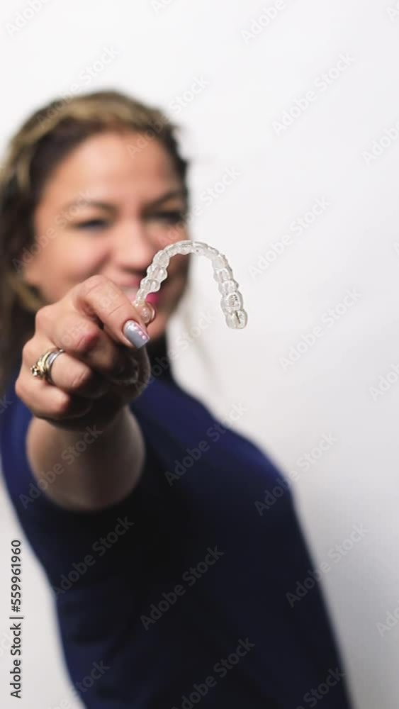 Adult smiling woman holding Invisalign braces in studio, dental healthcare and Orthodontic concept. Adult smiling woman holding Invisalign braces in studio, dental healthcare and Orthodontic concept.