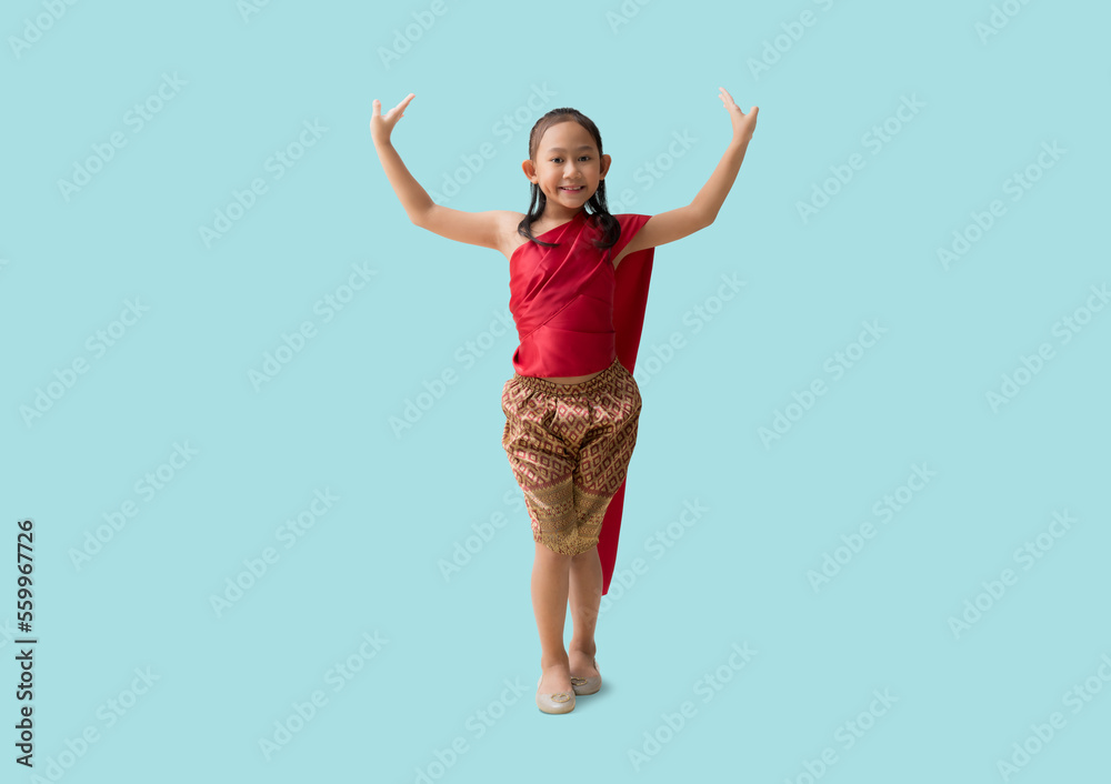 Full body Asian little girl in Thai national costumes with beautiful thai dance welcome of Thailand, isolated on pastel plain light blue background