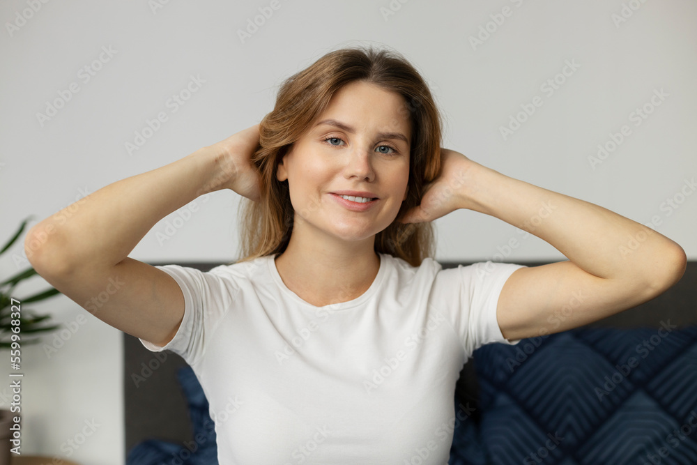 Portrait of smiling woman looking at camera with happy smile and touching her healthy hair. Beautiful female with long hair enjoying quality of her hair at home. Beauty concept Portrait of smiling woman looking at camera with happy smile and touching her healthy hair. Beautiful female with long hair enjoying quality of her hair at home. Beauty concept