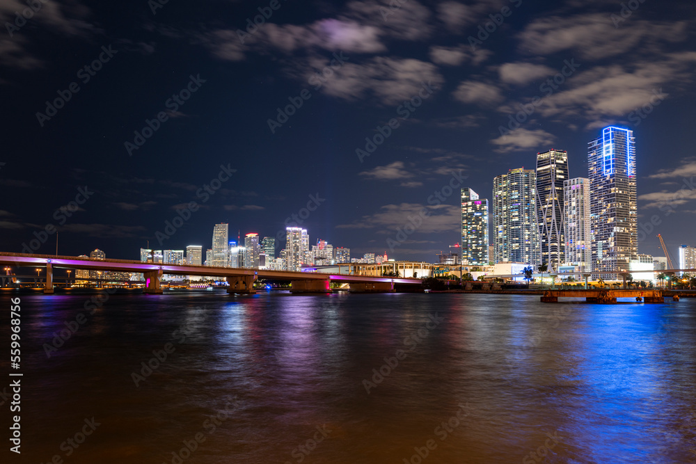 Miami city skyline panorama at night skyscrapers and bridge over sea with reflection Miami city skyline panorama at night skyscrapers and bridge over sea with reflection